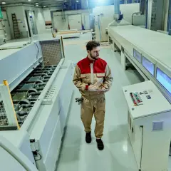 Pracownik w kombinezonie nadzoruje marszrutę produkcyjną, notując dane na tablecie.