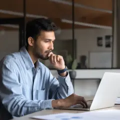 Mężczyzna w biurze pracuje przy laptopie, zastanawiając się, jaką pracę można wykonywać zdalnie.