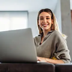 Uśmiechnięta kobieta pracuje na laptopie, odkrywając benefity na b2b.