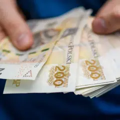 Dłonie trzymające stos banknotów 200 zł. Tak wyglądają zarobki w zawodach, które dużo zarabiają.