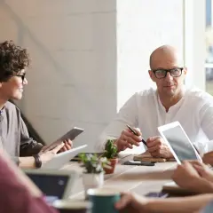 Zespół dyskutuje przy stole. Project manager ryczałt 8 5, omawiając strategię.