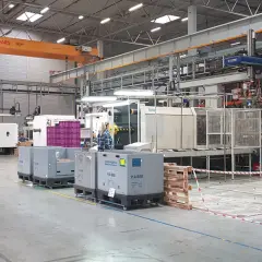 W hali produkcyjnej, podczas dni bezpieczeństwa, pracownicy nadzorują maszyny. W tle widoczny jest suwnica.