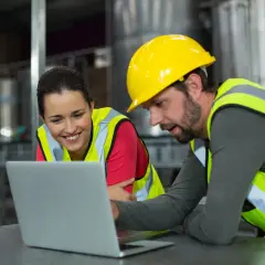 Pracownicy w kamizelkach odblaskowych i kaskach analizują dane na laptopie. Czy to usprawnienie procesów, czyli lean?