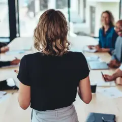 Uczestnicy szkolenia lean management słuchają prelegentki przy stole konferencyjnym.