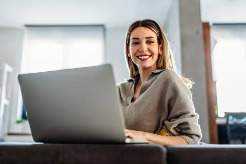 Uśmiechnięta kobieta pracuje na laptopie, odkrywając benefity na b2b.