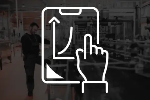 Wykres wzrostu na ekranie smartfona, symbolizujący kpi produkcja. Pracownik w tle obserwuje proces.