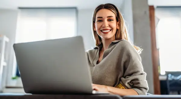 Uśmiechnięta kobieta pracuje na laptopie, odkrywając benefity na b2b.