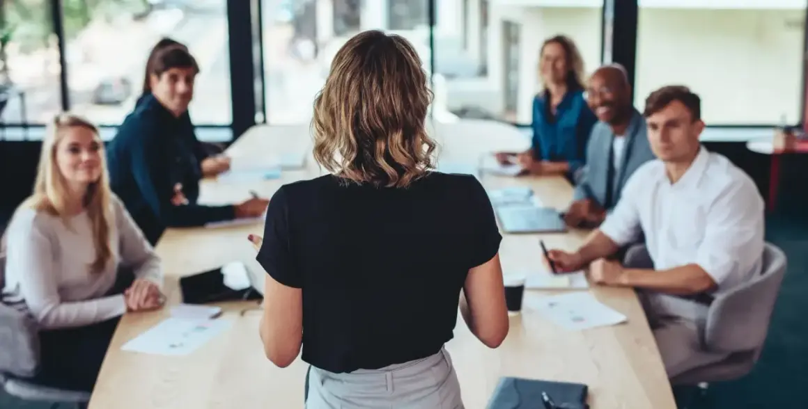 Uczestnicy szkolenia lean management słuchają prelegentki przy stole konferencyjnym.
