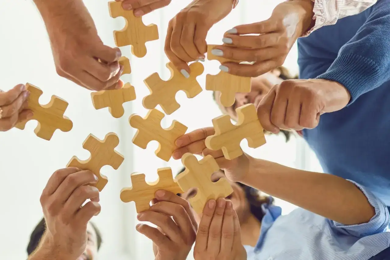 Zespół składa puzzle, symbolizując współpracę i realizację obowiązków kierownika.