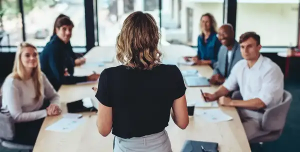 Uczestnicy szkolenia lean management słuchają prelegentki przy stole konferencyjnym.